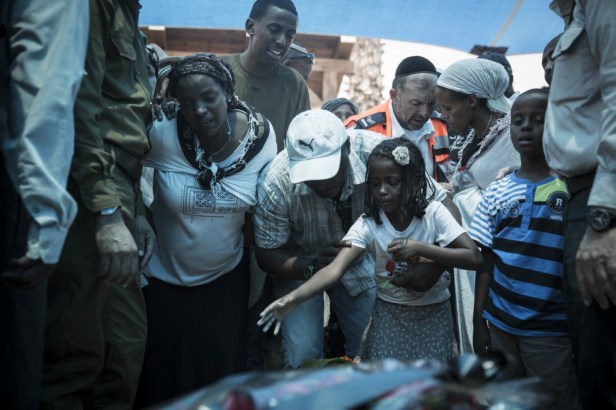 The wife and young daughter of Sergeant Major Bayhesain Kshaun cry over his fresh grave during the funeral ceremony at the Netivot military cemetery, July 22, 2014. Kshaun, 39, was killed by an anti-tank missile fired at the force responding to a terrorist infiltration incident on July 21. (Hadas Parush/Flash90)